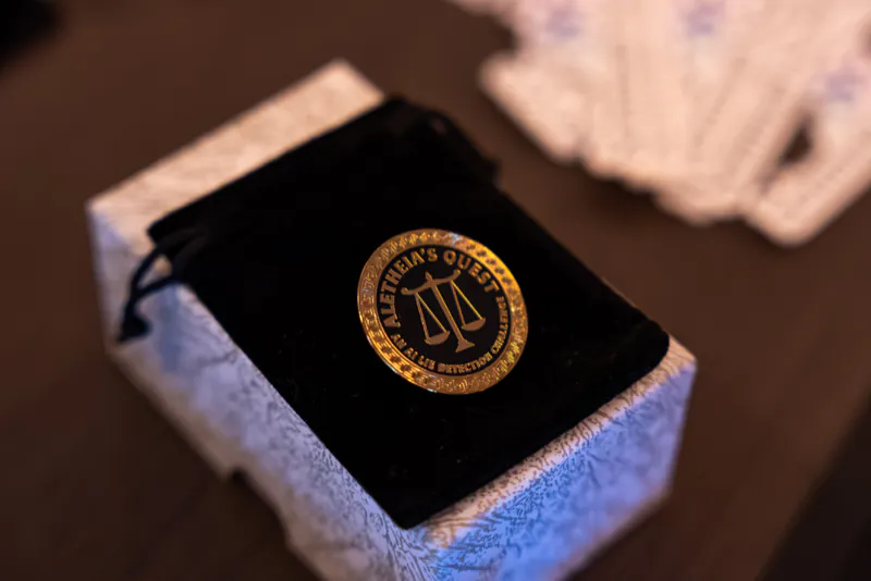 An Aletheia’s Quest medallion with a scales-of-justice emblem resting on a velvet pouch