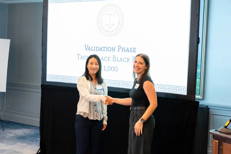 Two people shaking hands in front of the validation-phase third-place black-box award slide